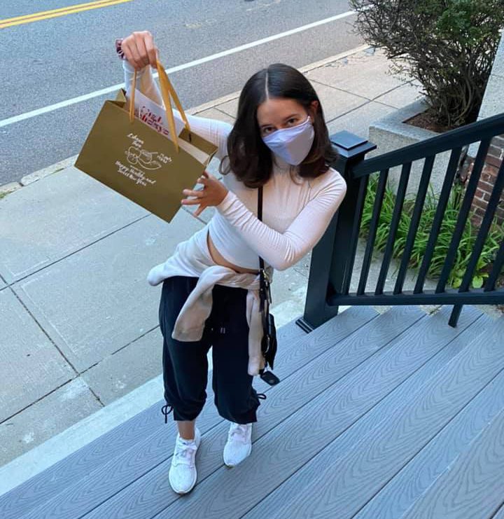 Young girl wearing mask and holding a bag of food